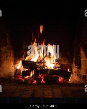 Fire burning in a fireplace, wood logs and bright flames. Warm home, heat. Christmas holiday Stock Photo