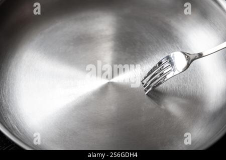 Fork inside a clean stainless steel pan Stock Photo