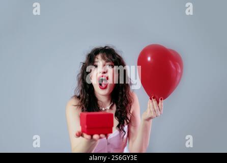 Happy girl receiving a Valentine's Day gift from her loved one, smiling with joy and excitement. Stock Photo