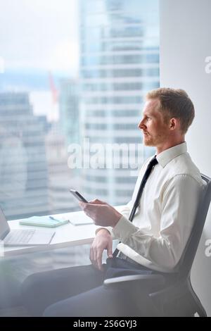 Busy happy professional business man using smartphone working in office. Stock Photo