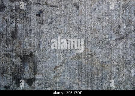 A rough gray concrete wall displays scratches and marks from wear, reflecting the passage of time and urban life, capturing an industrial feel. Stock Photo