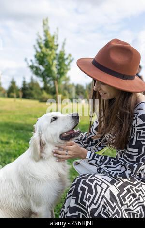 Young adult woman sitting with and smiling at golden retriever dog Stock Photo