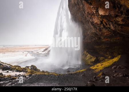 View from behind of the waterfall of Seljalandsfoss in winter. Skogar, Southern Region, Iceland, Europe. Stock Photo