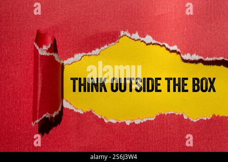 Think outside the box message written on ripped torn red paper on yellow background. Conceptual think outside the box symbol. Copy space. Stock Photo