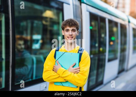 Smiling college student holding a binder and waiting for the tram Stock Photo