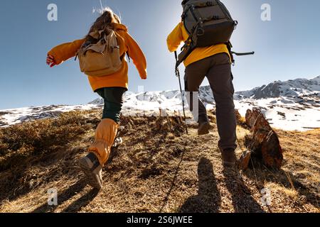 Couple of young active hikers are climbing uphill in mountains Stock Photo