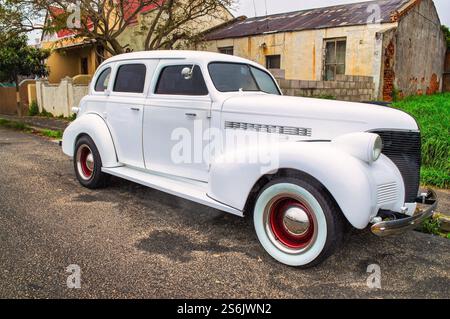 vintage car white rebuild, 1939, old, on the streets of Cape Town, South Africa, ruined building in the backgrounds Stock Photo