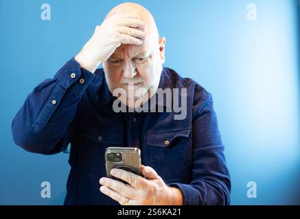 Older person concerned about on line fraud and being scammed on a smart phone Stock Photo