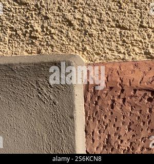 Detailed image showcasing the junction of different wall textures, illustrating construction materials and surface contrasts under natural sunlight. Stock Photo