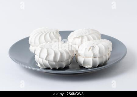 White marshmallows on gray plate on white background Stock Photo
