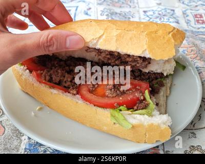 The Turkish kokoreç sandwich contains minced grilled lamb offal, tomato slices, and lettuce leaves Stock Photo