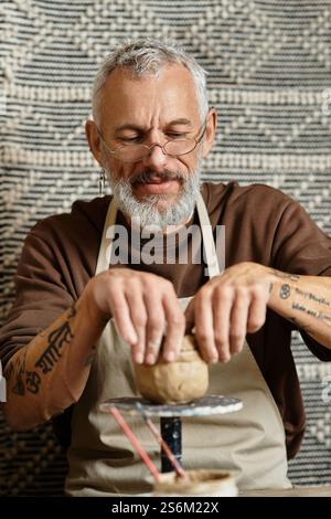 Bearded mature man and woman sculpting clay in pottery studio Stock ...
