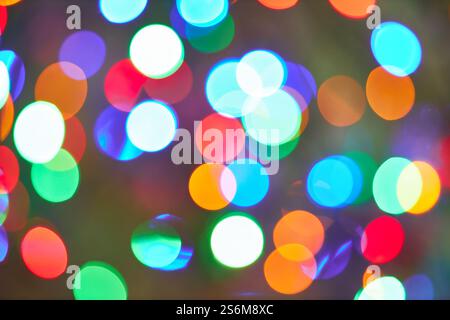 Festive bokeh lights in various colors create a vibrant and joyful background. The image features blurred circular shapes in green, red, blue, orange, Stock Photo