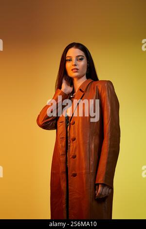 A young woman poses elegantly in trendy attire and stunning makeup. Stock Photo