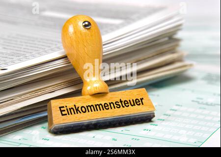 Einkommensteuererklärung beim Finanzamt Ein Holzstempel mit dem Aufdruck Einkommensteuer lehnt an einem Stapel Steuerformulare für das Finanzamt *** I Stock Photo