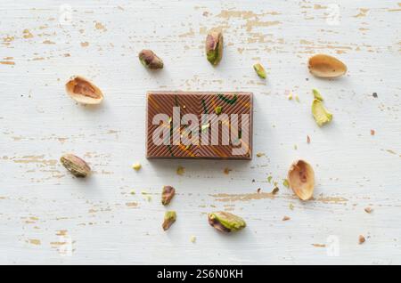 Piece of Dubai chocolate with pistachio paste and kunefe filled milk on white wooden background. Popular food concept. Horizontal orientation. Selecti Stock Photo