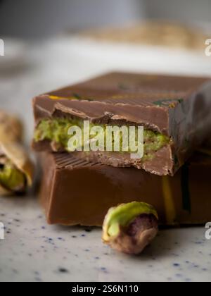 A piece of Dubai chocolate with pistachio paste and kunefe filled milk on a white background. Popular food concept. Vertical orientation. Macro photog Stock Photo