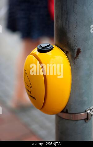 At a pedestrian crossing there is a yellow push button for a traffic light Stock Photo