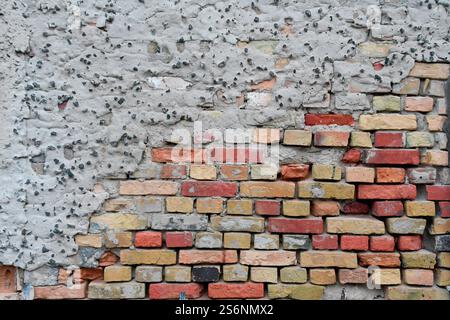 Crumbling plaster on brick wall Stock Photo