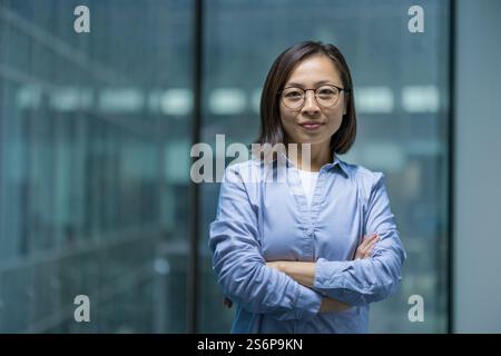 Portrait of confident serious woman inside office, Asian businesswoman looking focused at camera. Office worker working in evening. Stock Photo