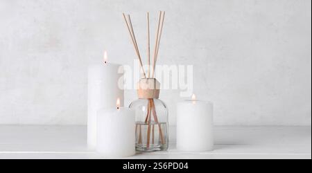 Burning candles and reed diffuser on white background Stock Photo