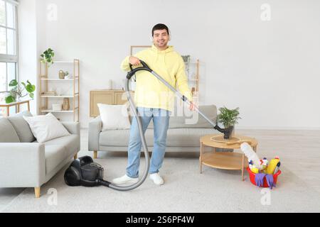 Young man vacuuming carpet in room Stock Photo