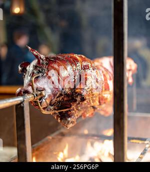 A pig is being cooked on a spit over a fire. The fire is hot and the smoke is rising. The scene is lively and energetic, with the pig being the main f Stock Photo
