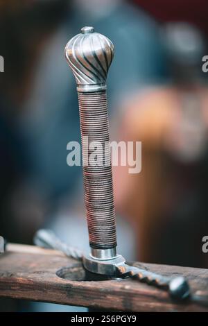 A sword with a silver handle and a gold tip. The sword is leaning on a wooden table Stock Photo