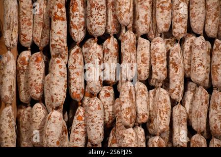 many air-dried sausages hanging in rows next to and on top of each other Stock Photo