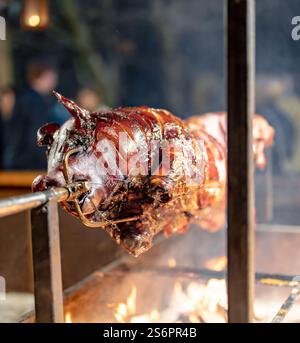 A pig is being cooked on a spit over a fire. The fire is hot and the smoke is rising. The scene is lively and energetic, with the pig being the main f Stock Photo