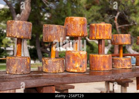 Rusty dumbbells resting on wooden bench in open park during sunny day Stock Photo