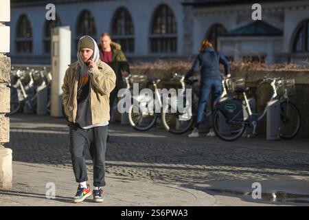 Ljubljana: young man walking while talking on the phone on Petkovskovo nabrezje (street). Slovenia Stock Photo