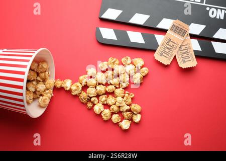 Movie clapper, sweet popcorn and tickets on red background, flat lay Stock Photo