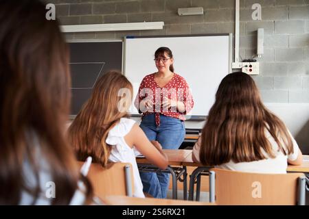High school teacher explaining lesson to students in classroom. Stock Photo