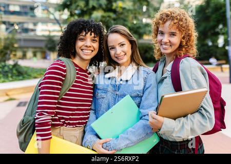 Three young university female students smiling together at camera on campus Stock Photo