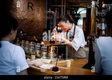 a female barista making coffee inside the largest Starbuck roastery in Tokyo using elegant technique and fancy coffee making accessory Stock Photo