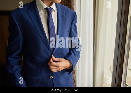 Individual in blue suit jacket, adjusting attire, formal clothing, smart business look, corporate style concept Stock Photo