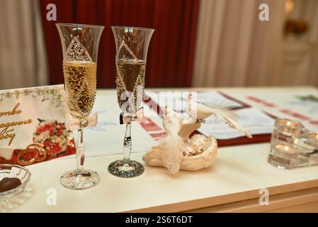 Champagne flutes elegantly adorned with bows and doves, set on a wedding table celebrating marriage in a romantic ambiance, concept Stock Photo