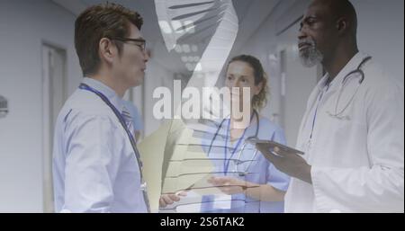 DNA strand image over medical professionals discussing in hospital corridor Stock Photo