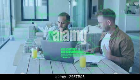 Green digital data image over two men working on laptops at table Stock Photo