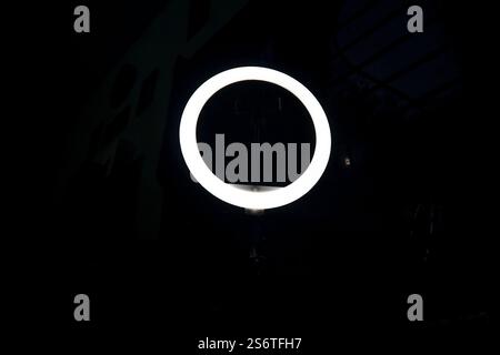 A glowing ring light in a dark room, illuminating its surroundings. Stock Photo
