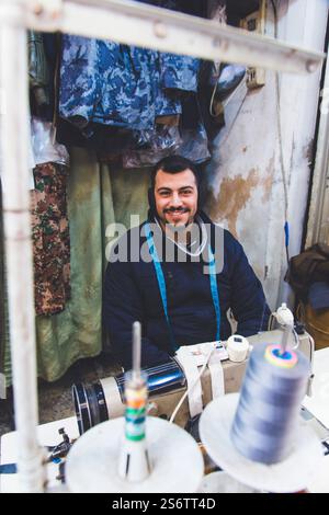 Jordan, Middle East, Amman. Al Balad district, smiling young man behind his sewing machine Stock Photo