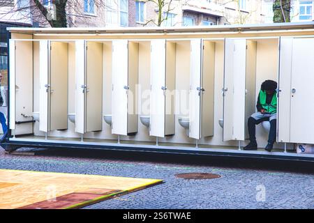 Responsible for the cleanliness of the toilets, sitting with his phone Stock Photo