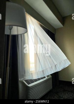 Curtains billowing above an air conditioner unit in a hotel. Stock Photo