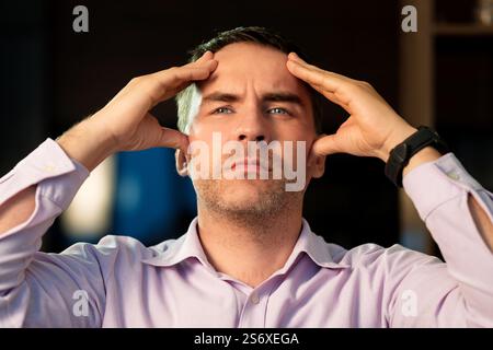 Exhausted male suffer from headache. Tired and successful worker. Deadline. The employee is angry. Worried young man holding his face. Tired man holdi Stock Photo