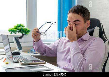 Businessman office working holding sore head pain from desk working and sitting all day using laptop computer suffering headache sick worker overworki Stock Photo