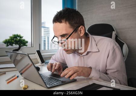 Thoughtful it developer thinking about fixing software bugs on netbook. contemplative male student watching tutorial on web site learning online via l Stock Photo