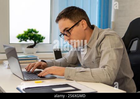 portrait of his he nice attractive focused professional guy coding programming supporting website remotely at modern work place station. the young man Stock Photo