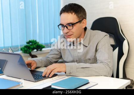 Thoughtful it developer thinking about fixing software bugs on netbook. contemplative male student watching tutorial on web site learning online via l Stock Photo
