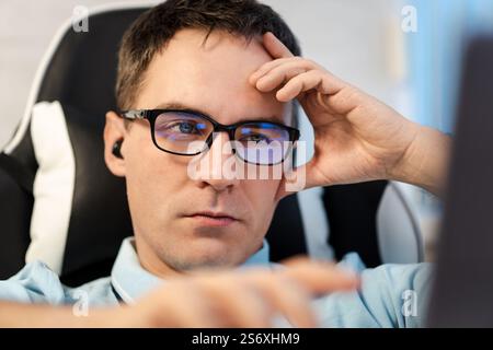 He is using touchpad while reading an e-mail on laptop. Multi-tasking businessman working in the office. man works in a bright office during the day Stock Photo